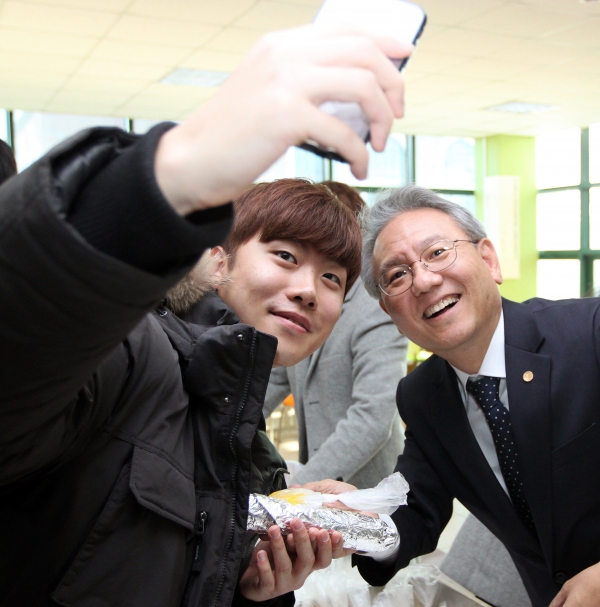 간식을 나누며 학생과 신민규 총장이 사진을 찍고 있다