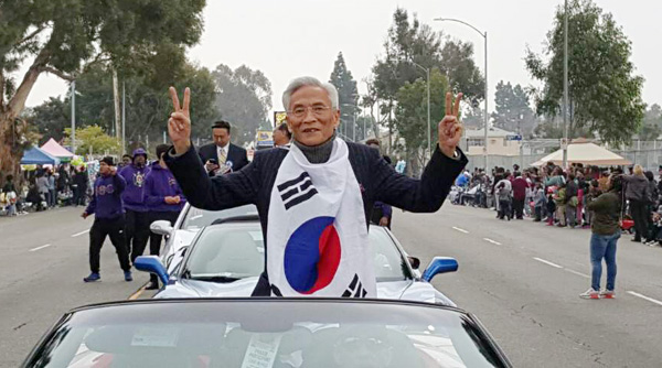 마틴 루터 킹 목사 기념일 카퍼레이드 행사에 참석한 권 집사가 태극기를 목에 두르고 거리의 환영인파를 향해 손을 흔들며 답례하고 있다.