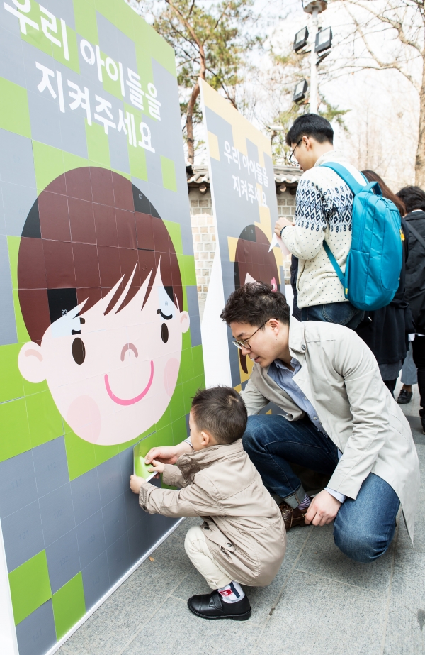 아동학대로 고통받는 아이들에게 웃는 얼굴을 되찾아 주기 위해 시민참여 행사로 진행된 캠페인에서 한 가족이 스티커를 붙이고 있다. 