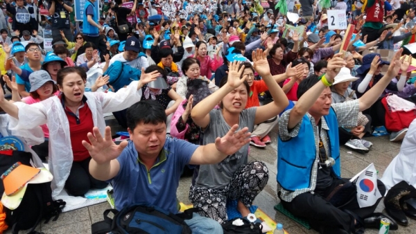 '2016 서울광장 동성애 퀴어축제반대 국민대회'에서 플래카드를 들고 간절히 기도하고 있는 참가자들.