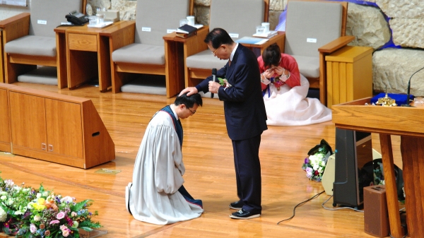 아버지 김삼환 목사(가운데 선 이)가 아들 김하나 목사(왼편 무릎 꿇은 이)에게 안수기도를 하고 있다. 