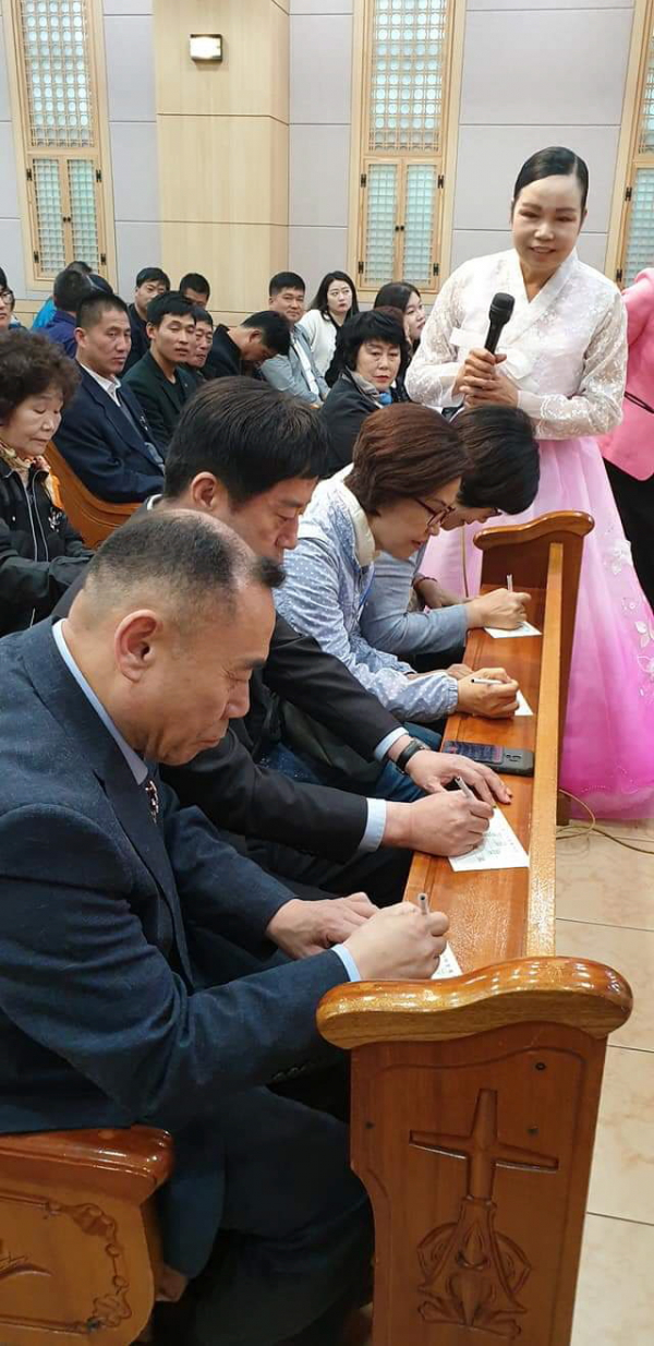 구순연 집사가 집회 중 교회 등록카드를 작성하고 있는 새신자들을 바라보고 있다.