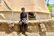 파키스탄 홍수 피해 당시 세이브더칠드런에서 제공한 텐트 앞에 앉아있는 아메드 칸(8세, 가명).