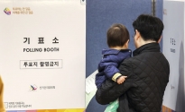제22대 국회의원 선거일인 10일 서울 종로구 경희궁자이2단지아파트 주민공동시설에 마련된 투표소를 찾은 유권자가 아이와 함께 기표소로 들어가고 있다.