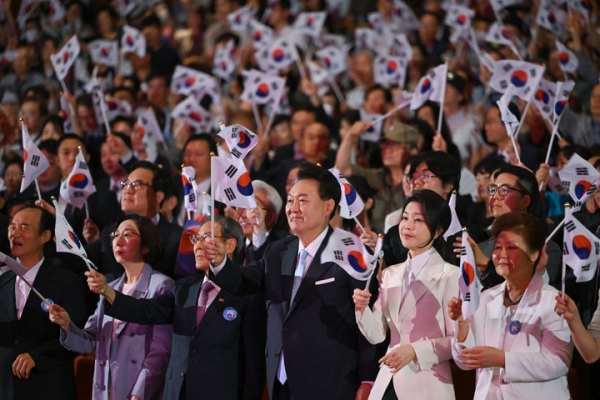 윤석열 대통령과 부인 김건희 여사가 15일 서울 종로구 세종문화회관에서 열린 제79주년 광복절 경축식에서 광복절의 노래에 맞춰 태극기를 흔들고 있다.