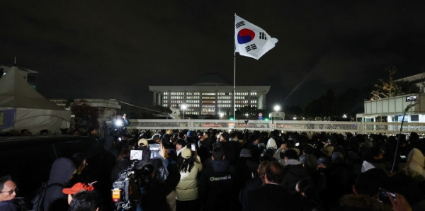 윤석열 대통령의 비상계엄 해제 요구 결의안이 국회 본회의에서 통과된 4일 새벽 서울 영등포구 국회 정문 앞에서 시민들 모습.