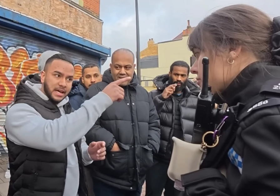 런던에서 한 여성 경찰관이 무슬림 남성 무리의 항의에 맞서 기독교 거리 설교자의 권리를 옹호하고 있다