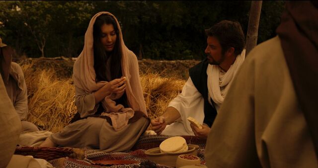 뮤지컬 영화 ‘룻기 원 뉴 맨’의 한 장면으로, 룻 역의 배우와 보아스가 타작마당에서 함께 앉아 음식을 나누며 이야기를 나누는 모습. 