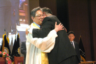 예성 직전총회장 이동석 목사(오른쪽)가 신임총회장 김원교 목사에게 가운을 입혀주고 포옹하고 있다.