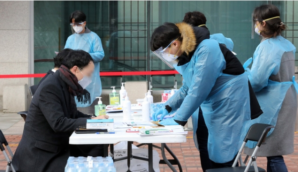 명성교회 부목사가 신종 코로나바이러스 감염증(코로나19) 확진 판정을 받은 가운데 26일 오전 서울 강동구 명성교회에 앞에 설치된 선별진료소에서 주민들이 진료를 받기 위해 서류를 작성하고 있다. 