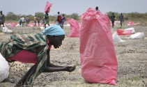 2018년 5월 내전의 남수단에서 한 여성이 WFP가 공중투하한 식량 사탕수수 알갱이를 손으로 쓸어모으고 있다