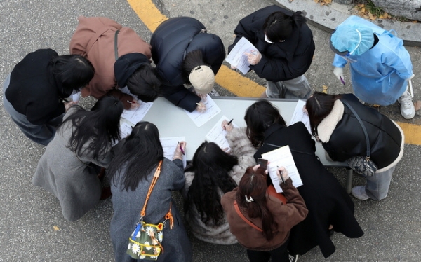 이틀 연속 신종 코로나 바이러스 감염증(코로나19) 확진자가 500여명대를 보인 27일 오후 서울 강서구보건소에서 시민들이 코로나19 검사를 받기 전 기초역학조사서를 작성하고 있다