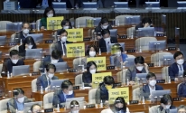 정의당 의원들이 26일 서울 여의도 국회 본회의에서 가덕도 관련 법안을 비판하는 피켓을 의석에 붙여 놓고 있다.