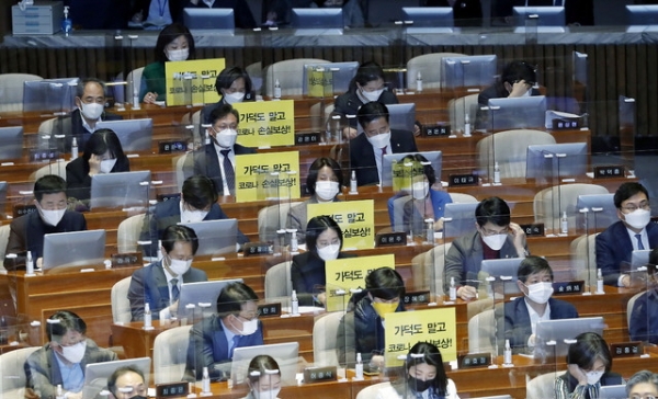 정의당 의원들이 26일 서울 여의도 국회 본회의에서 가덕도 관련 법안을 비판하는 피켓을 의석에 붙여 놓고 있다.