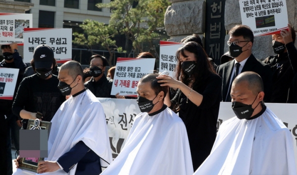  코로나19 백신 피해자가족협의회(코백회)의 '진실을 찾기 위한 헌법소원청구' 기자회견이 열린 28일 오전 서울 종로구 헌법재판소 앞에서 파해자가족 대표들이 삭발을 하고 있다